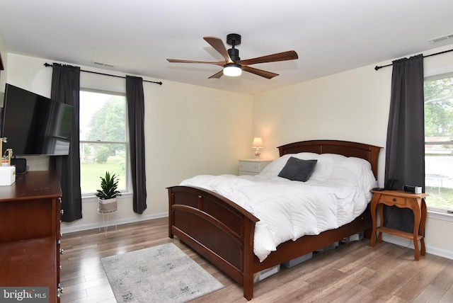 bedroom with wood-type flooring, multiple windows, and ceiling fan