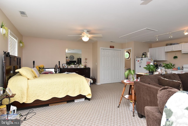 carpeted bedroom featuring ceiling fan, white refrigerator, and a closet