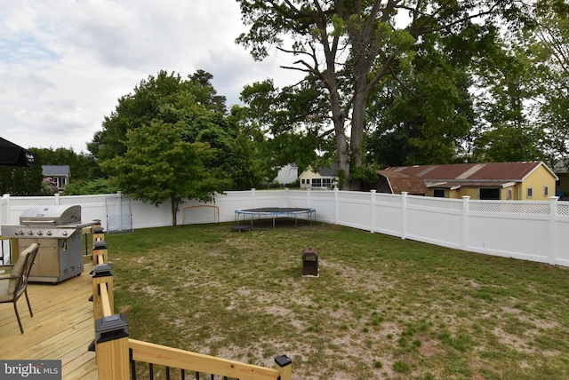 view of yard featuring a trampoline and a wooden deck