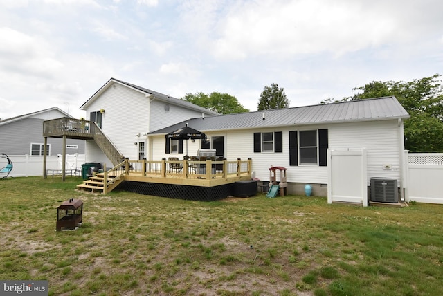 rear view of property featuring a lawn, a deck, and central air condition unit