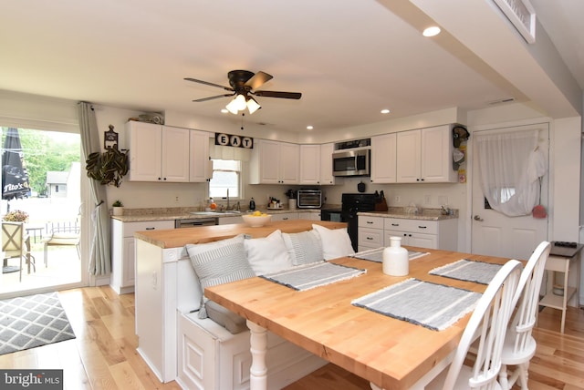 dining room with ceiling fan, light wood-type flooring, and sink