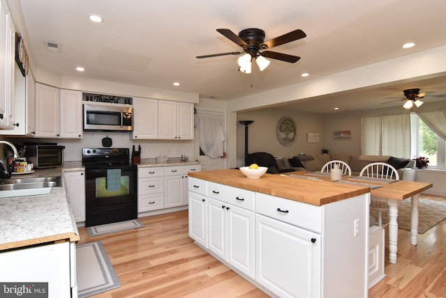 kitchen with wooden counters, light wood-type flooring, black range with electric cooktop, sink, and white cabinetry