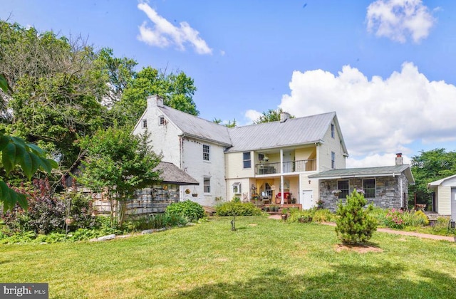 back of property with a balcony and a yard