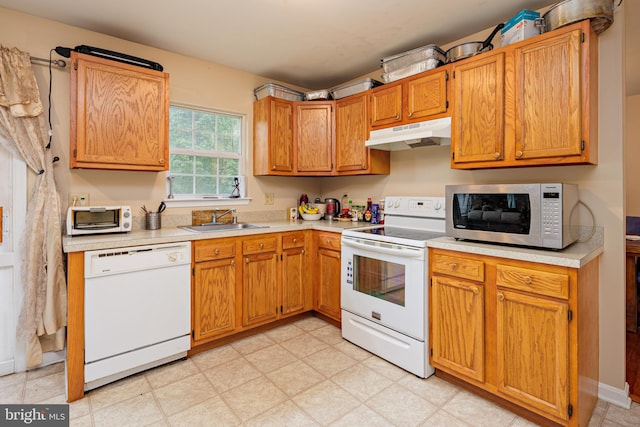 kitchen with white appliances, sink, and light tile floors