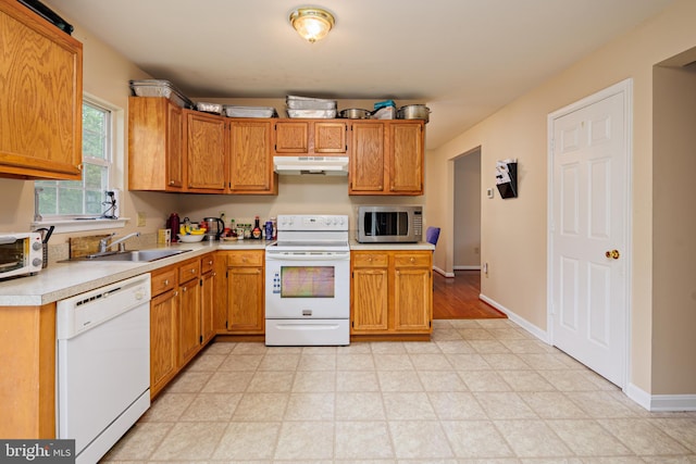 kitchen featuring white appliances, sink, and light tile floors