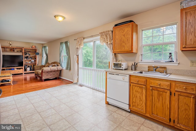 kitchen with dishwasher, sink, and light hardwood / wood-style floors