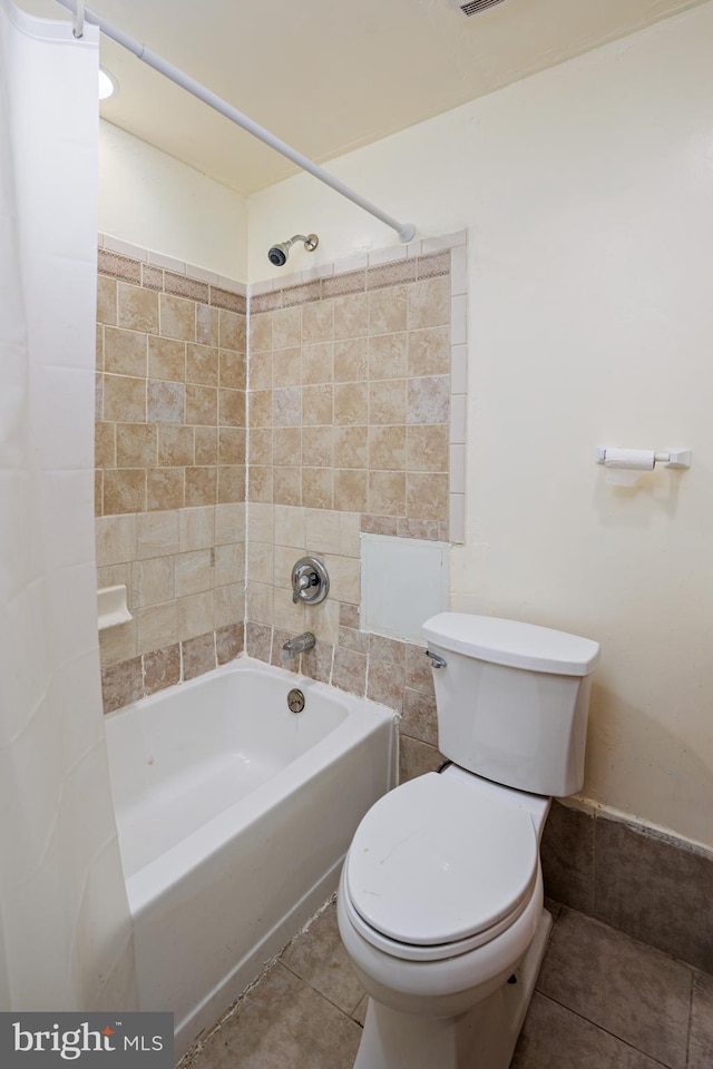 bathroom with tile flooring, tiled shower / bath combo, and toilet