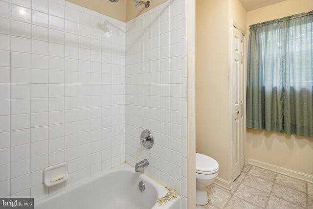 bathroom with tile floors, tiled shower / bath combo, and toilet