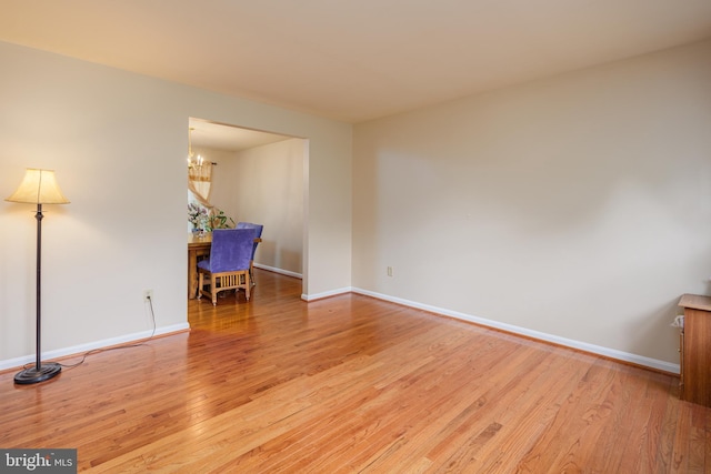 unfurnished room featuring a chandelier and light wood-type flooring