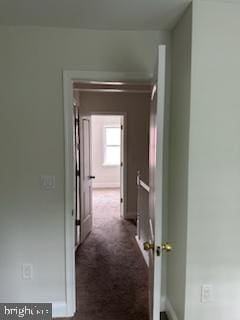 hall featuring dark colored carpet