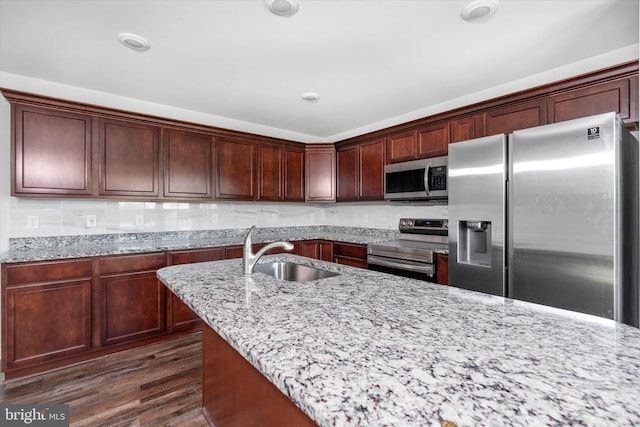 kitchen featuring stainless steel appliances, light stone counters, dark wood-type flooring, and sink