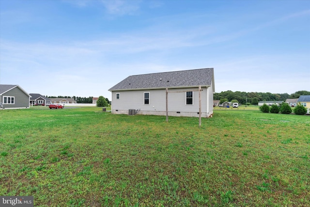 back of house with central AC unit and a yard