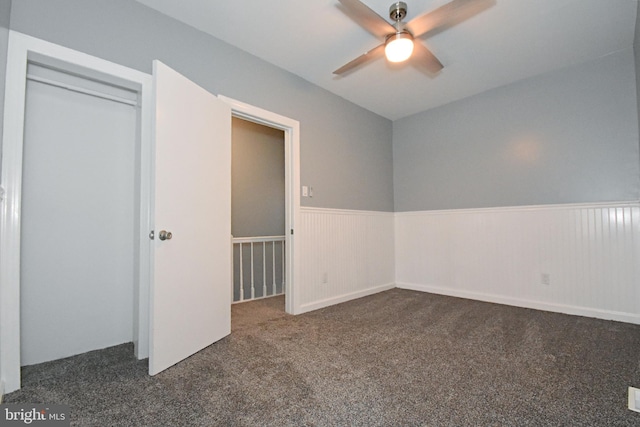 unfurnished room with dark colored carpet and ceiling fan