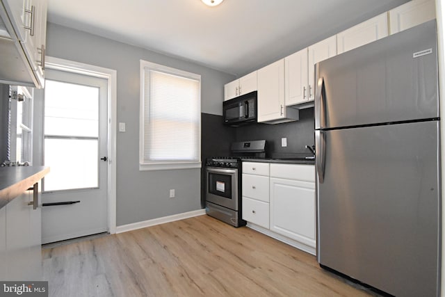 kitchen featuring stainless steel appliances, white cabinets, and light hardwood / wood-style flooring