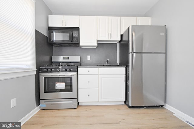 kitchen with stainless steel appliances, light hardwood / wood-style floors, and white cabinets