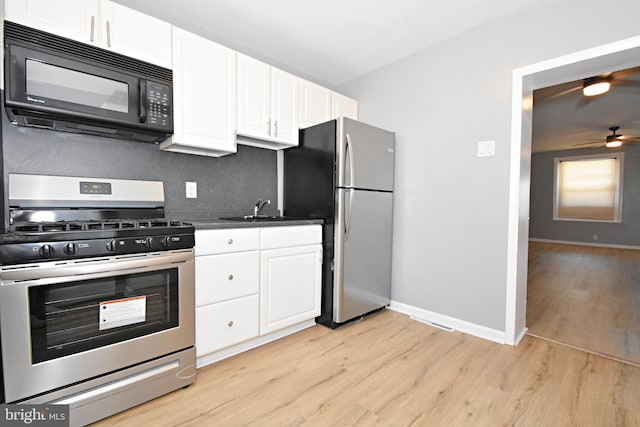 kitchen with appliances with stainless steel finishes, white cabinetry, ceiling fan, and light hardwood / wood-style floors