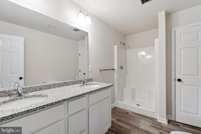 bathroom featuring walk in shower, hardwood / wood-style flooring, toilet, and double sink vanity