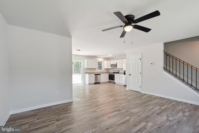 unfurnished living room featuring ceiling fan, light hardwood / wood-style floors, and sink