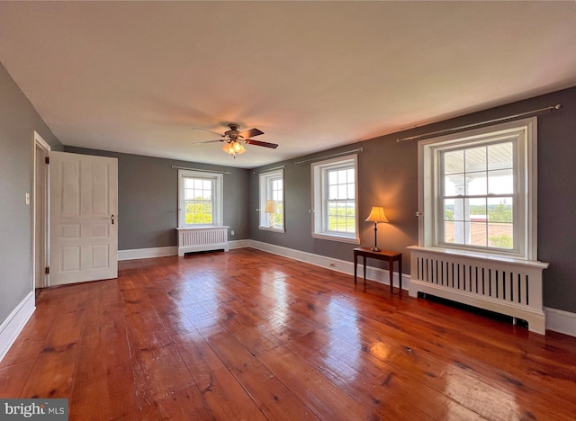 interior space featuring ceiling fan, hardwood / wood-style floors, radiator heating unit, and a healthy amount of sunlight