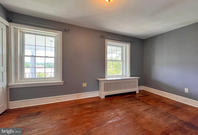 unfurnished room featuring radiator and dark hardwood / wood-style floors