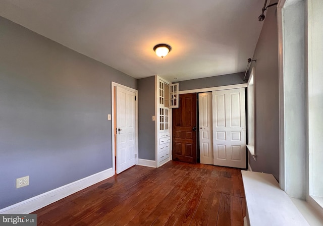 unfurnished bedroom with a closet and dark hardwood / wood-style floors