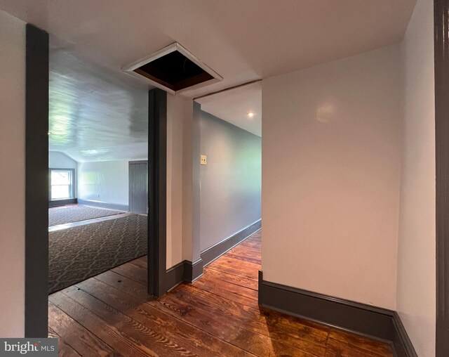 corridor with vaulted ceiling and dark hardwood / wood-style flooring