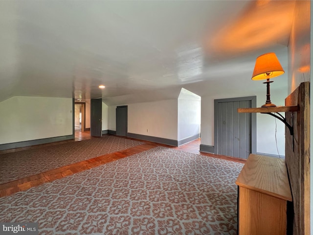 bonus room featuring lofted ceiling and dark hardwood / wood-style flooring