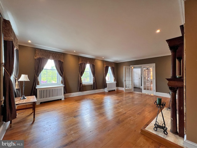 living room with radiator heating unit, light hardwood / wood-style flooring, french doors, and crown molding