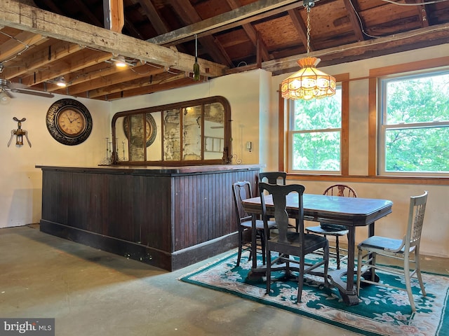 dining space featuring concrete flooring, lofted ceiling, and indoor bar