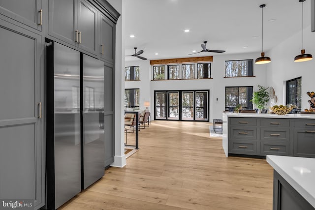 kitchen with stainless steel refrigerator, open floor plan, gray cabinets, light countertops, and pendant lighting