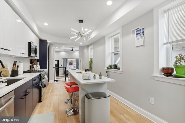 kitchen with white cabinets, light wood-type flooring, stainless steel appliances, and sink