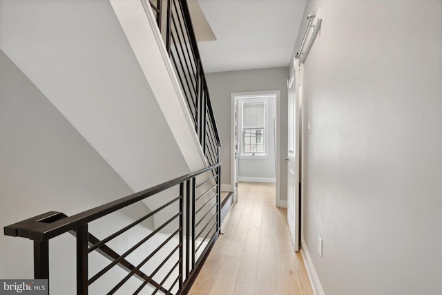 hallway with a barn door and light wood-type flooring