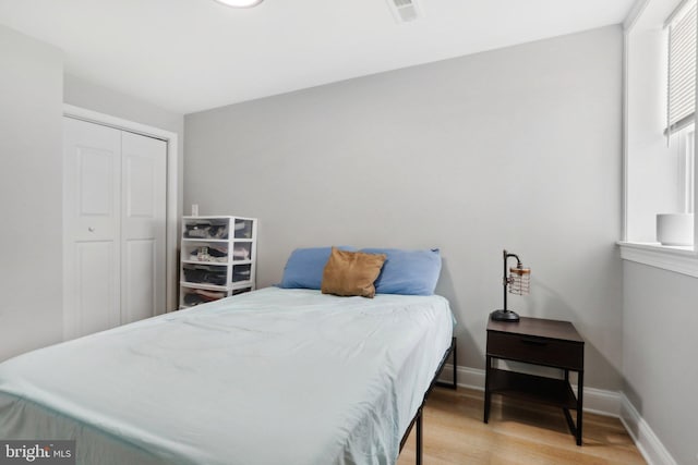 bedroom with light hardwood / wood-style floors and a closet