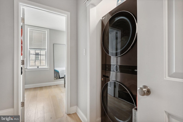 clothes washing area with light hardwood / wood-style floors and stacked washer / dryer