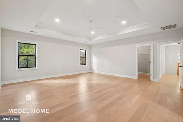 unfurnished room with a raised ceiling and light wood-type flooring