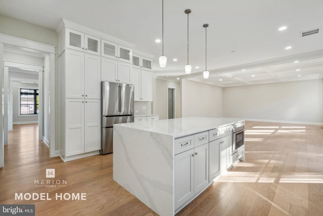 kitchen featuring light stone countertops, a center island, light hardwood / wood-style flooring, white cabinets, and appliances with stainless steel finishes