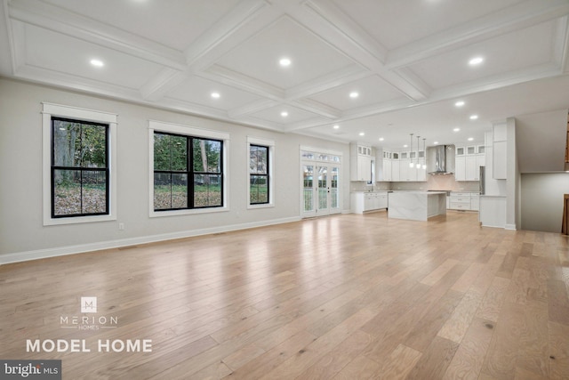 unfurnished living room with beamed ceiling, light wood-type flooring, and coffered ceiling