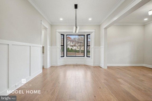 unfurnished dining area featuring light hardwood / wood-style floors, crown molding, and a chandelier