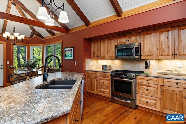 kitchen featuring stainless steel appliances, vaulted ceiling with beams, decorative light fixtures, an inviting chandelier, and sink