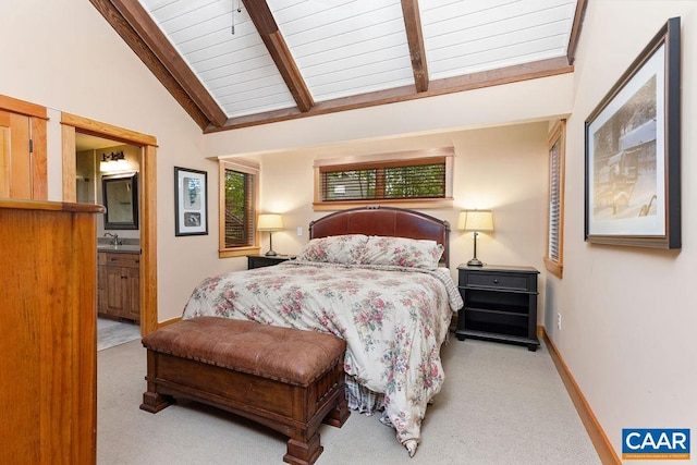 carpeted bedroom featuring sink, vaulted ceiling with beams, and ensuite bath