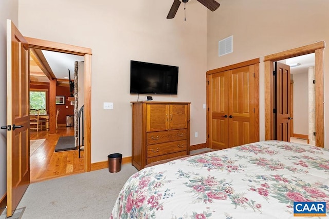 carpeted bedroom with a high ceiling, a closet, and ceiling fan