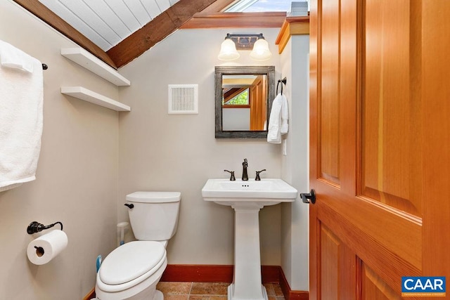 bathroom featuring tile flooring, vaulted ceiling with beams, and toilet