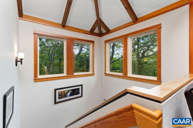 stairway featuring a healthy amount of sunlight and lofted ceiling with beams