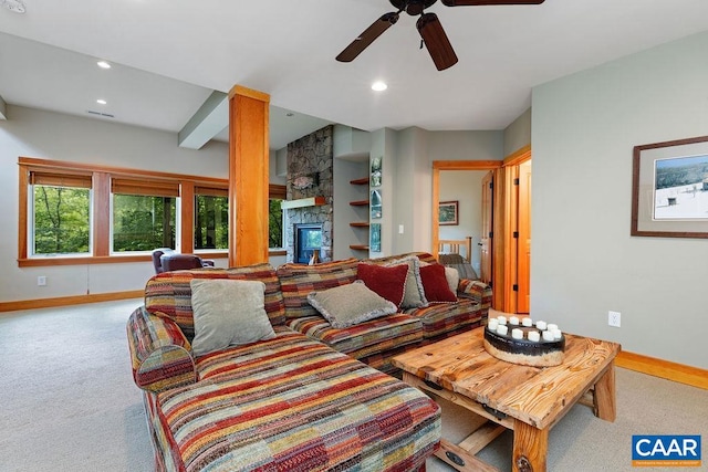 living room with a stone fireplace, carpet, and ceiling fan