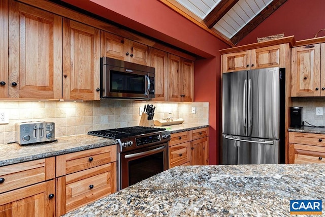 kitchen featuring appliances with stainless steel finishes, light stone counters, tasteful backsplash, and vaulted ceiling