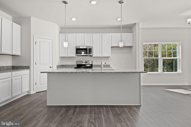 kitchen featuring decorative light fixtures, stainless steel appliances, white cabinetry, and a kitchen island with sink