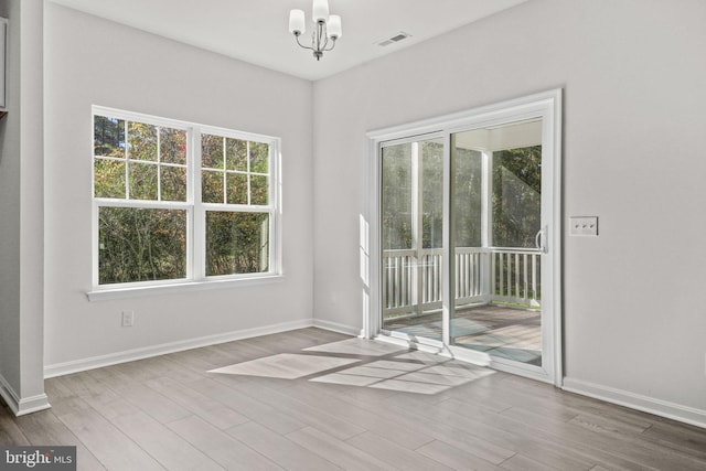 spare room with wood-type flooring and an inviting chandelier