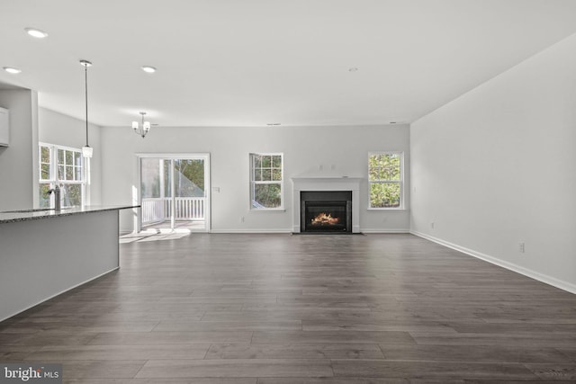 unfurnished living room with dark hardwood / wood-style flooring, plenty of natural light, a notable chandelier, and sink