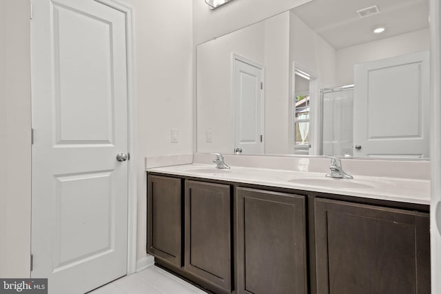 bathroom with tile patterned flooring, vanity, and walk in shower