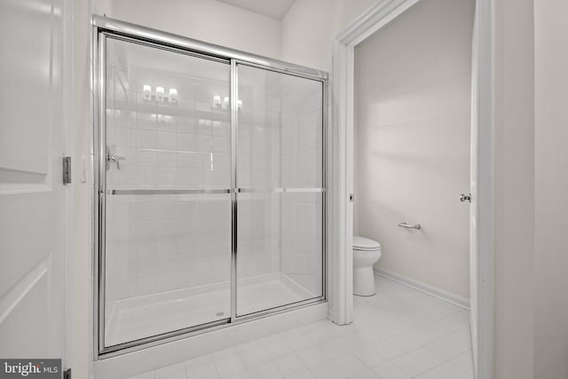 bathroom featuring tile patterned floors, toilet, and a shower with door